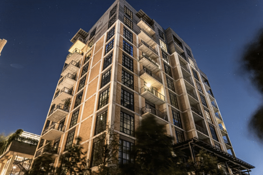 Low-angle, nighttime shot of a tall apartment building with exposed balconies and brick facade.